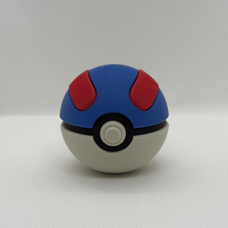 May include: A blue, red, and white Pok&eacute; Ball. The top half is blue with two red circular shapes. The bottom half is white with a black band and a white circle in the center.