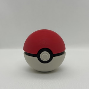 May include: A red and white Pok&eacute; Ball with a black band and a central button. The top half is red, the bottom half is white, and the button is black with a white center. A classic design.