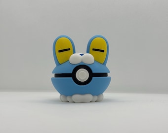 May include: A blue and white cartoon character with yellow ears and black accents. The character has a round body with a black circle in the center. The character is a collectible item.
