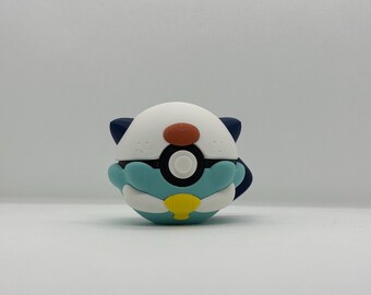 May include: A colorful, round, cartoon-style accessory featuring a white top with a brown nose and dark blue ears. The lower half is light blue with a yellow accent. A black and white circle is in the center.