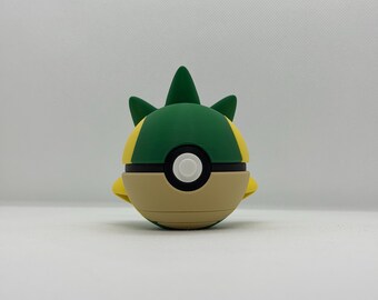 May include: A colorful, spherical toy with a green, yellow, and tan design. The toy has a black band around the middle with a white circle in the center. The top has green spikes.
