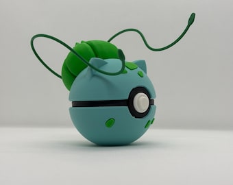 May include: A light blue and green spherical figurine with a black stripe and white button. The figurine has green accents and two green tendrils extending from the top. The figurine is a representation of a popular character.