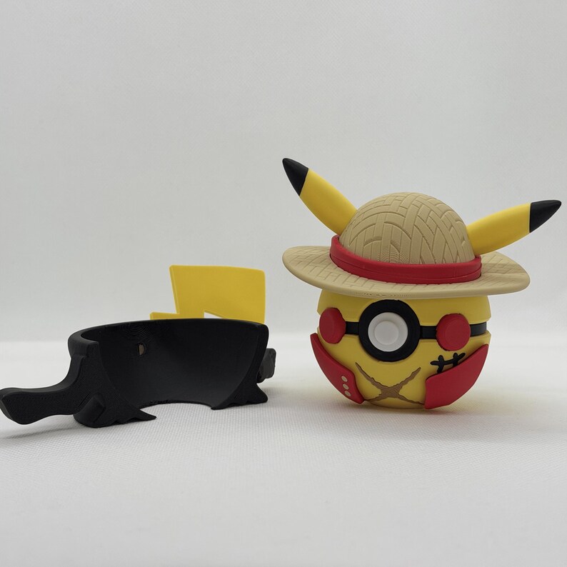 May include: A yellow Pikachu figure wearing a straw hat with a red band and black-rimmed glasses. The figure has black accents and red details. A black accessory and a yellow lightning bolt are also present.