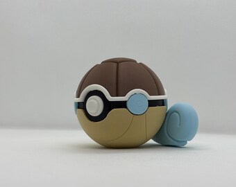 May include: A novelty item in brown, tan, white, and blue, shaped like a turtle. It features a brown, segmented top, a tan base, and a white and blue circular design. A light blue turtle head and legs are attached.