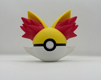 May include: A white, yellow, and red decorative figure resembling a stylized ball with wing-like features. The figure has a yellow top with red accents and a black stripe, and a white bottom with a black circle in the center.