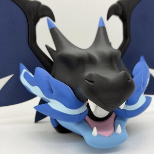 May include: A 3D-printed dragon figurine in black, blue, and pink. The dragon has a detailed head with sharp teeth, blue accents, and large wings. The figurine is a collectible item.