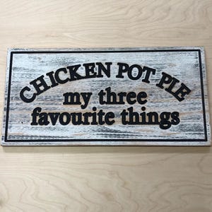 Puede incluir: Un letrero de madera blanco con letras negras que dice "Chicken Pot Pie my three favourite things".
