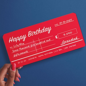 May include: A red and white novelty cheque with the text "Happy Birthday" and a handwritten amount of "£7,550". The cheque is made out to "Lily May" and signed "Grandad".