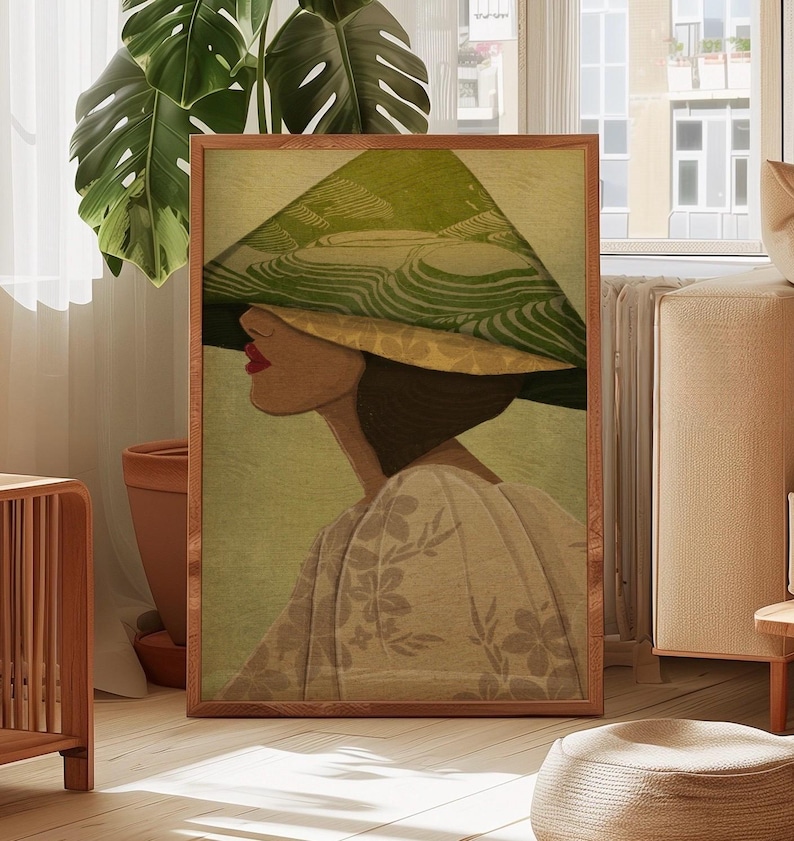 May include: A framed art print depicting a woman in profile, wearing a large, green and yellow hat. The artwork has a vintage style, with a soft colour palette of greens, yellows, and beige. The woman is wearing a floral patterned dress.