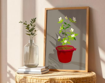 May include: A framed art print featuring a red flower pot with a plant bearing white flowers and green leaves. The artwork is set against a gray background. A clear glass vase with greenery and a stack of books are on a woven table.