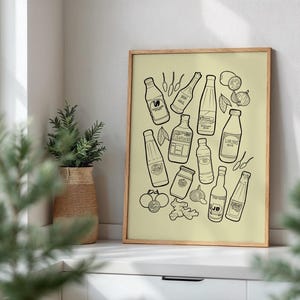 May include: A framed print featuring a collection of illustrated condiment bottles, jars, and ingredients in black and white. The artwork includes various sauces, spices, and vegetables, creating a culinary theme. The print is displayed on a white surface near a window.