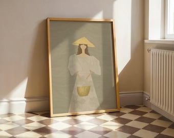 May include: Framed art print featuring a woman in a white dress and yellow hat, holding a yellow basket. The artwork has a minimalist style with a neutral color palette, leaning against a wall. The frame is made of light-colored wood.
