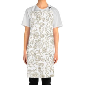 May include: White apron featuring a repeating pattern of food illustrations in brown tones. The apron has a neck strap and a waist tie. The food illustrations include various dishes, drinks, and cooking utensils.