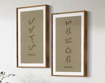 May include: Two framed prints with brown wooden frames and beige backgrounds. The prints feature stylized text in brown, with the words "PAMILYA" and "PAGIBIG" at the bottom.