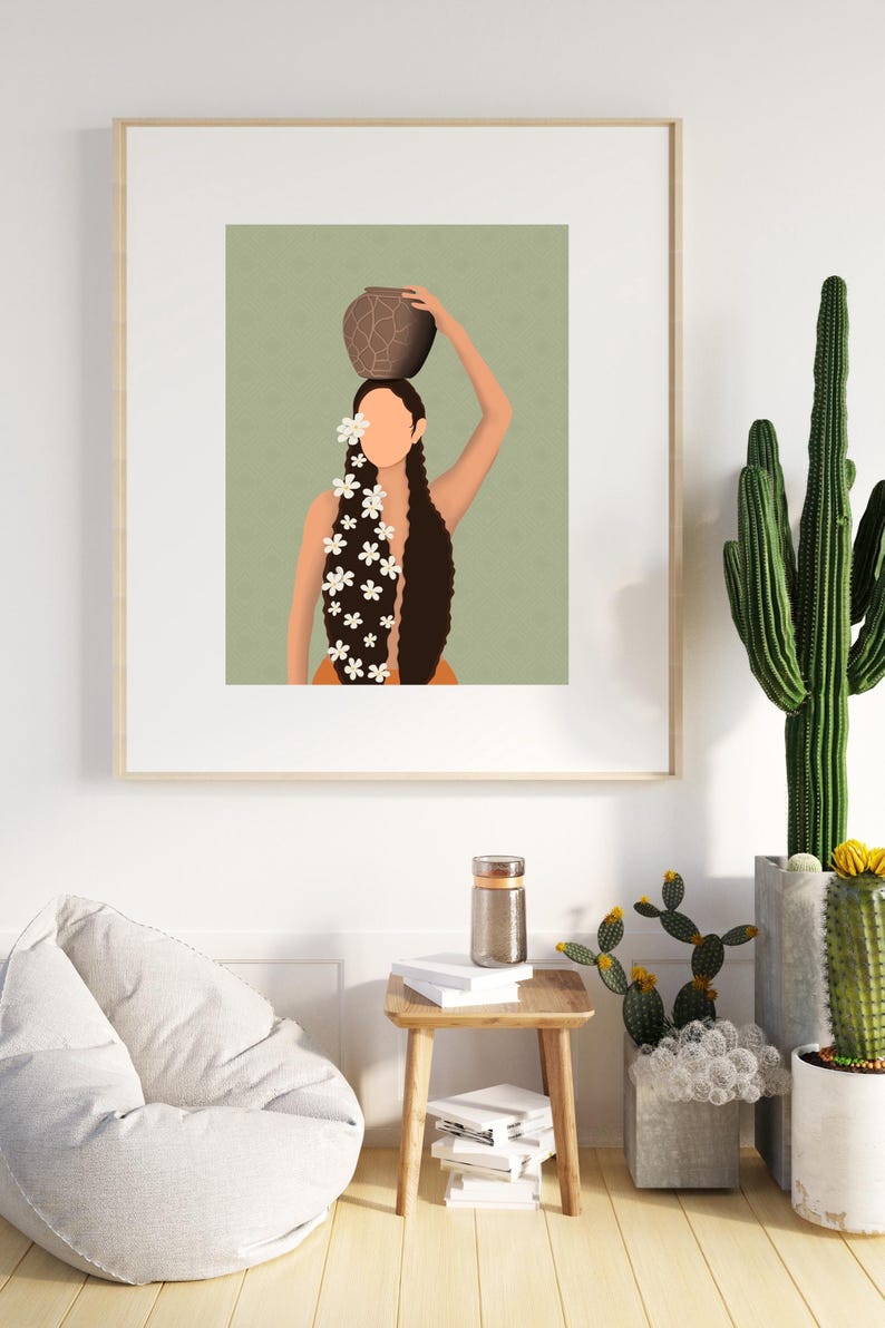 May include: Art print of a person carrying a brown pot on their head, with long dark hair adorned with white flowers. The artwork is framed and displayed on a white wall, with a wooden side table and cacti in the foreground.