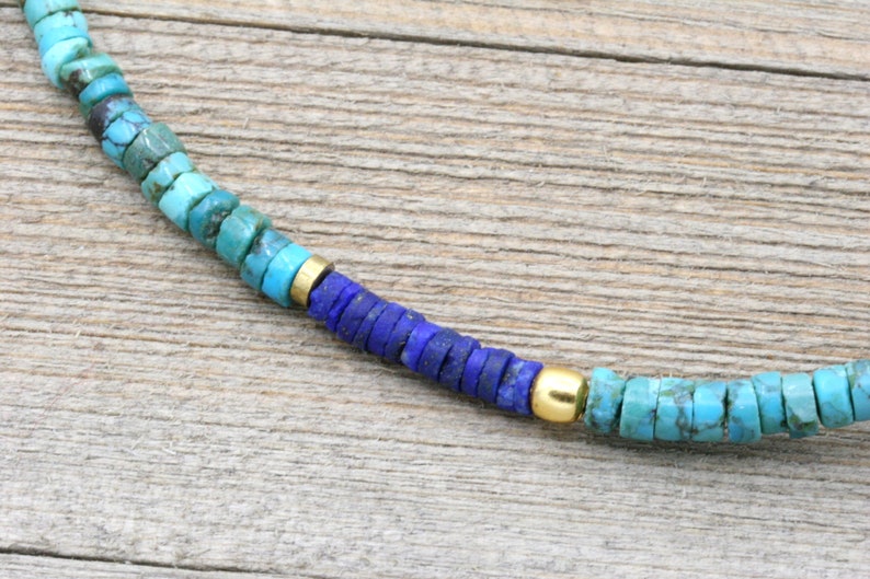 Puede incluir: Un collar de cuentas de turquesa y lapisl&aacute;zuli con detalles dorados. El collar est&aacute; hecho de peque&ntilde;as cuentas redondas y tiene un degradado de color, comenzando con turquesa y pasando a lapisl&aacute;zuli.