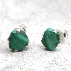 May include: A pair of silver earrings with green malachite stones. The stones are irregularly shaped and have a natural, organic look.