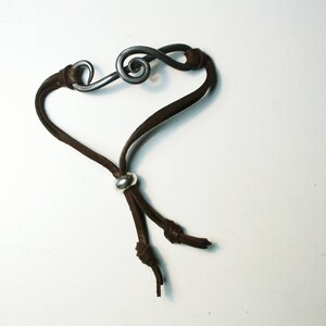 May include: A brown leather bracelet with a silver treble clef charm and a silver bead accent.