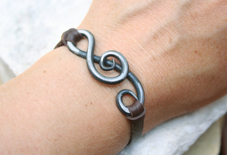 May include: A brown leather bracelet with a silver metal treble clef charm.