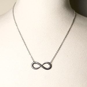 May include: A silver infinity symbol pendant necklace on a silver chain.