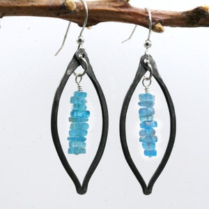May include: A pair of silver earrings with a teardrop-shaped frame and a dangle of light blue gemstone chips.