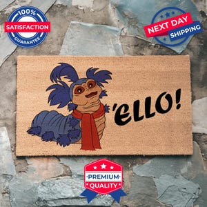 May include: A brown coir doormat with a blue and red cartoon worm with a red scarf and the text 'ello!'.