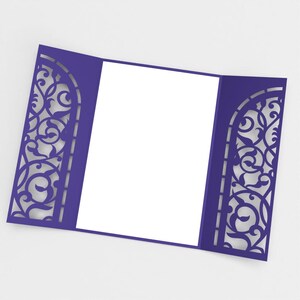 May include: A purple invitation card with intricate, laser-cut floral designs on the left and right sides. The card is open, revealing a blank white space for text. The overall design is elegant and suitable for weddings or special events.