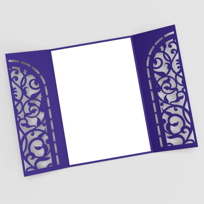 May include: A royal blue invitation card with a decorative, laser-cut design. The card is open, revealing a blank white space for text. The intricate pattern on the sides adds an elegant touch, suitable for weddings or special events.