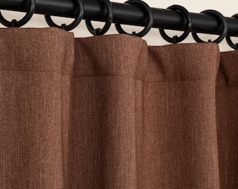 May include: Brown curtains with a textured weave hanging on a black curtain rod with silver rings.