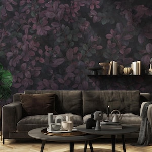Può includere: Un divano grigio scuro con una coperta di lana marrone scuro e un cuscino marrone scuro. Il divano è di fronte a una parete con un motivo di carta da parati floreale scuro. Ci sono oggetti decorativi su uno scaffale sopra il divano.