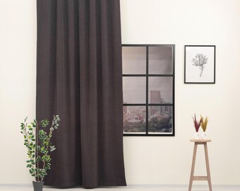 May include: A dark brown curtain hangs from a black curtain rod in front of a window with a view of a city skyline. The curtain is made of a textured fabric and has a simple, elegant design.
