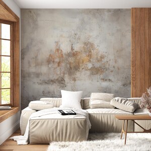 May include: A white sectional sofa with cushions sits in a living room with a textured grey and brown wall, a wooden floor, and a wooden coffee table with a vase of dried flowers.