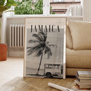 May include: A framed poster featuring a black and white image of a palm tree and a bus on a beach in Jamaica. The word "JAMAICA" is printed at the top, with "CARIBBEAN" below. The poster is displayed on a woven rug.
