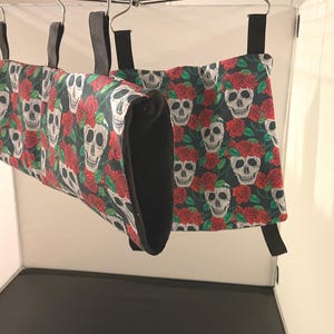 May include: Three hanging fabric tunnels with a black and white skull and red rose pattern. The tunnels are made of a soft, plush fabric and are perfect for small animals to play in.