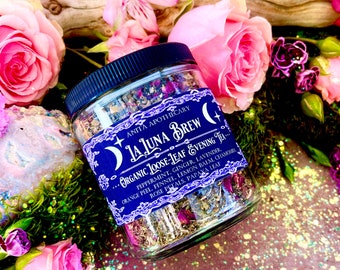 May include: A glass jar filled with a blend of dried herbs and flowers, labeled "La Luna Brew Organic Loose-Leaf Evening Tea". The label lists ingredients including peppermint, ginger, lavender, orange peel, fennel, lemon balm, chamomile, rose petals, and papaya leaf.