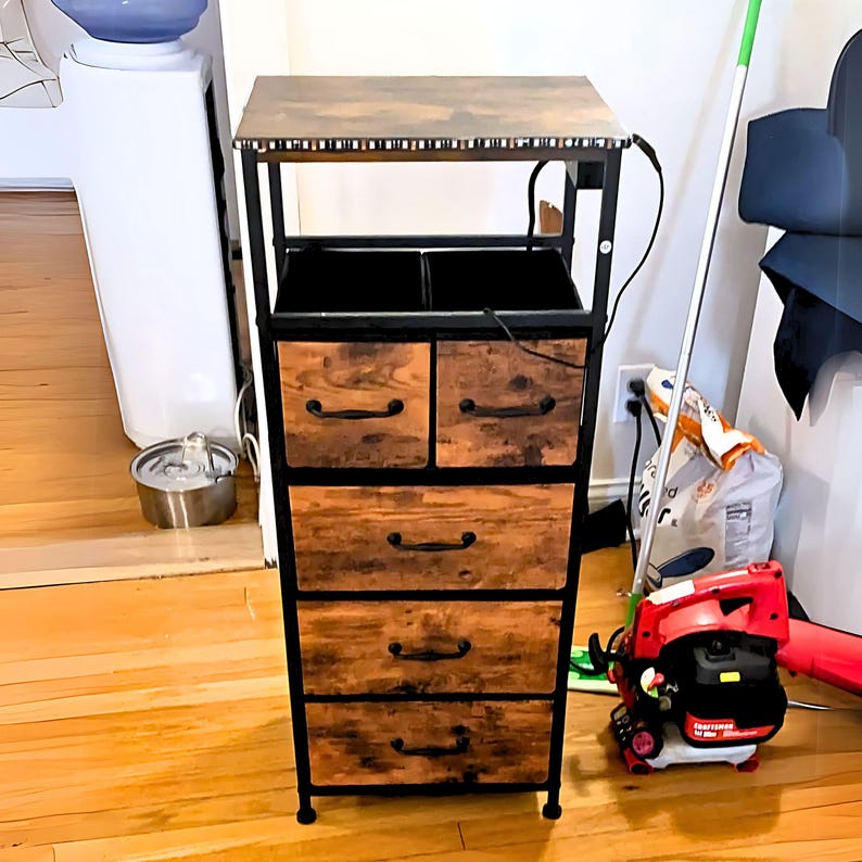 May include: A five-drawer metal storage cabinet with a wooden top and a black metal frame. The cabinet has a rustic brown finish and black metal drawer pulls. The cabinet is standing on a wooden floor.