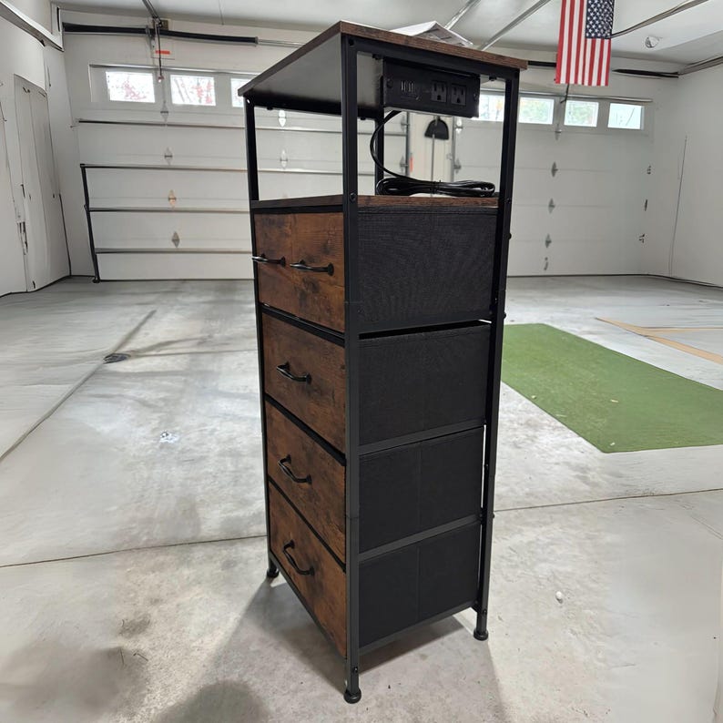 May include: A brown and black metal 4-drawer dresser with a black top shelf. The top shelf has a built-in power strip with a cord hanging down.