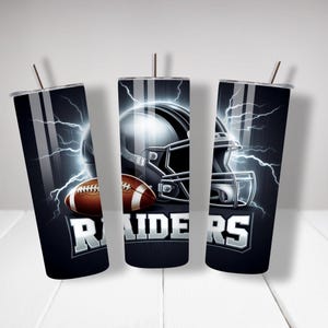 May include: Three black and silver tumblers featuring a football helmet and football design. The tumblers have the word "RAIDERS" printed on them.