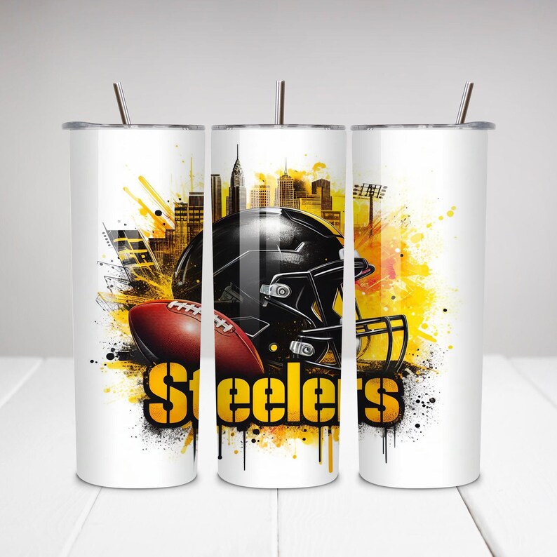 Op de afbeelding: Witte beker met een footballhelm en football, met een stadsgezicht en gele en zwarte accenten. Het woord "Steelers" wordt in grote, gele letters weergegeven. De beker heeft een zilveren rietje.