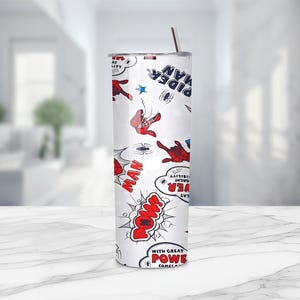 May include: A white tumbler featuring a comic book style design with Spider-Man graphics. The design includes red and blue Spider-Man figures, speech bubbles with words like "POW" and "MAN", and the text "Spider-Man". A stainless steel straw is inserted in the lid.