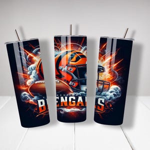 Op de afbeelding: Drie zwarte en oranje roestvrijstalen bekers met een voetbalhelm en een rookontwerp. De bekers hebben de tekst "Cincinnati Bengals" erop.