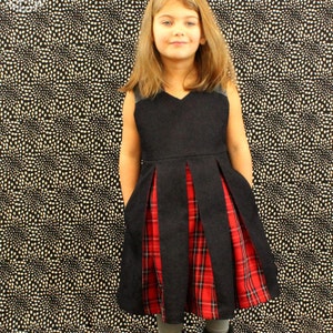 May include: A black denim dress with a red and black plaid skirt. The dress has a V-neck and is sleeveless.