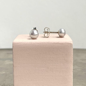 Könnte beinhalten: Ein Paar silberne Perlmutt-Ohrstecker mit einem silbernen Stift und einem Schmetterlingsverschluss.