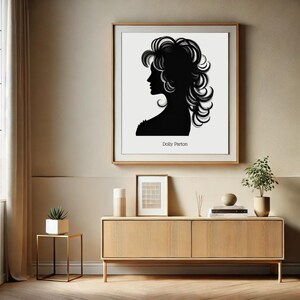 以下が含まれることがあります： 額縁に入った、白黒のシルエットで描かれたドリー・パートンの絵。絵は木製のキャビネットの上の壁に飾られている。