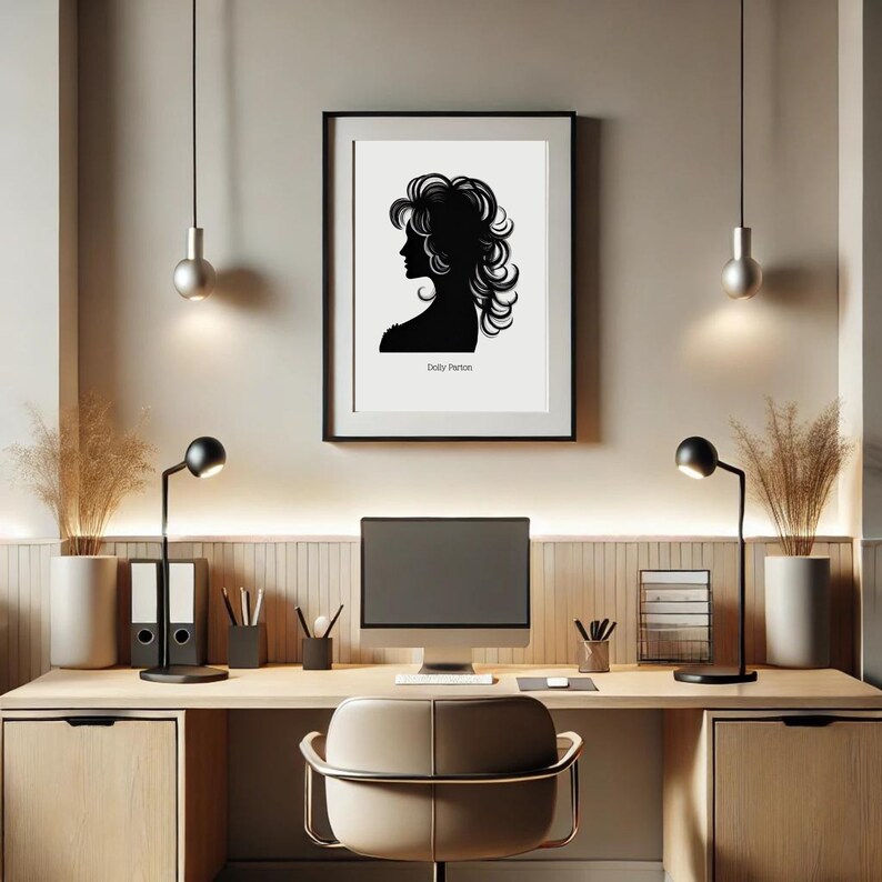 以下が含まれることがあります： 木製の机、2つの黒いランプ、コンピューターモニター、椅子、そしてドリー・パートンのシルエットの白黒の額装されたプリントがある、自宅のオフィスワークスペース。