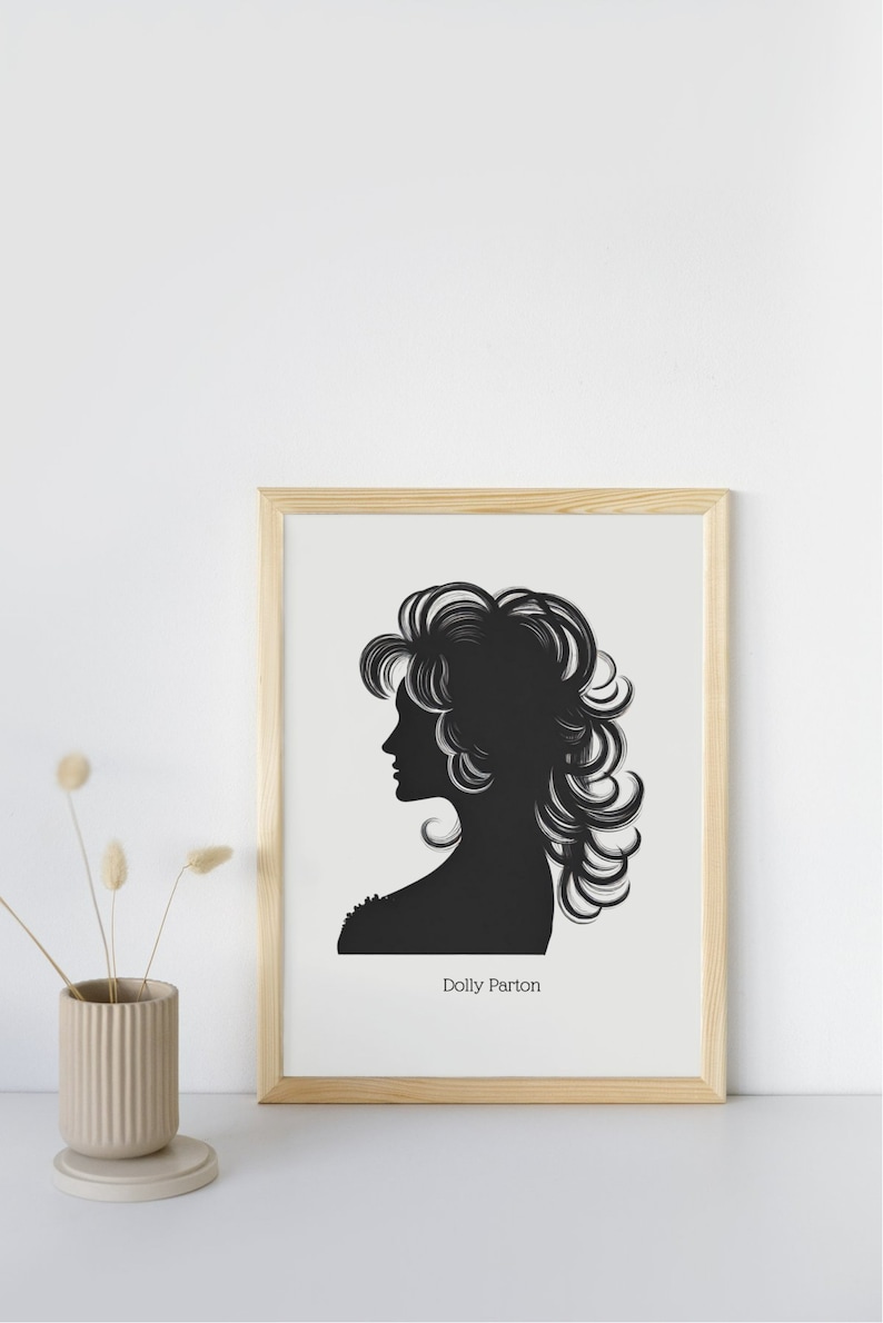 以下が含まれることがあります： 「Dolly Parton」というテキストが画像の下にある、Dolly Partonのシルエットの白黒の額装されたプリントです。