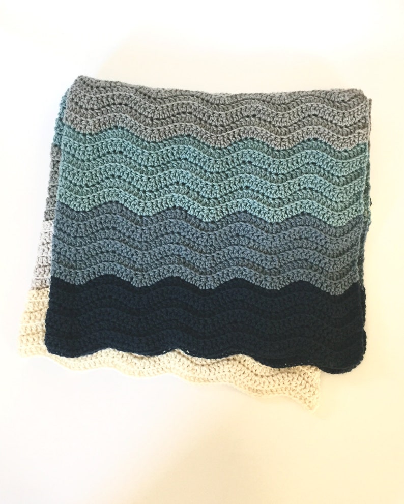 May include: A crocheted blanket with a wavy pattern in shades of blue, gray, and white.