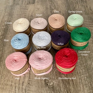 May include: Assortment of 12 skeins of yarn in various colors, including cream, blue, sky blue, indigo, greenbrier green, spring green, silver, doe, pink, blush (lighter), and huckleberry red. Each skein is labeled with the yarn color and "Appalachian Baby Yarn".