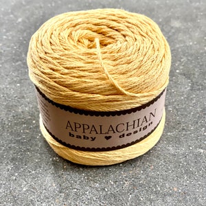 May include: A skein of yellow cotton yarn with a brown label that reads "Appalachian Baby Design".