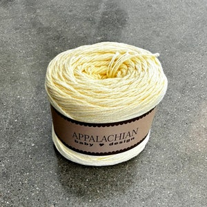 May include: A ball of pale yellow yarn with a brown label that reads "Appalachian Baby &hearts; Design".
